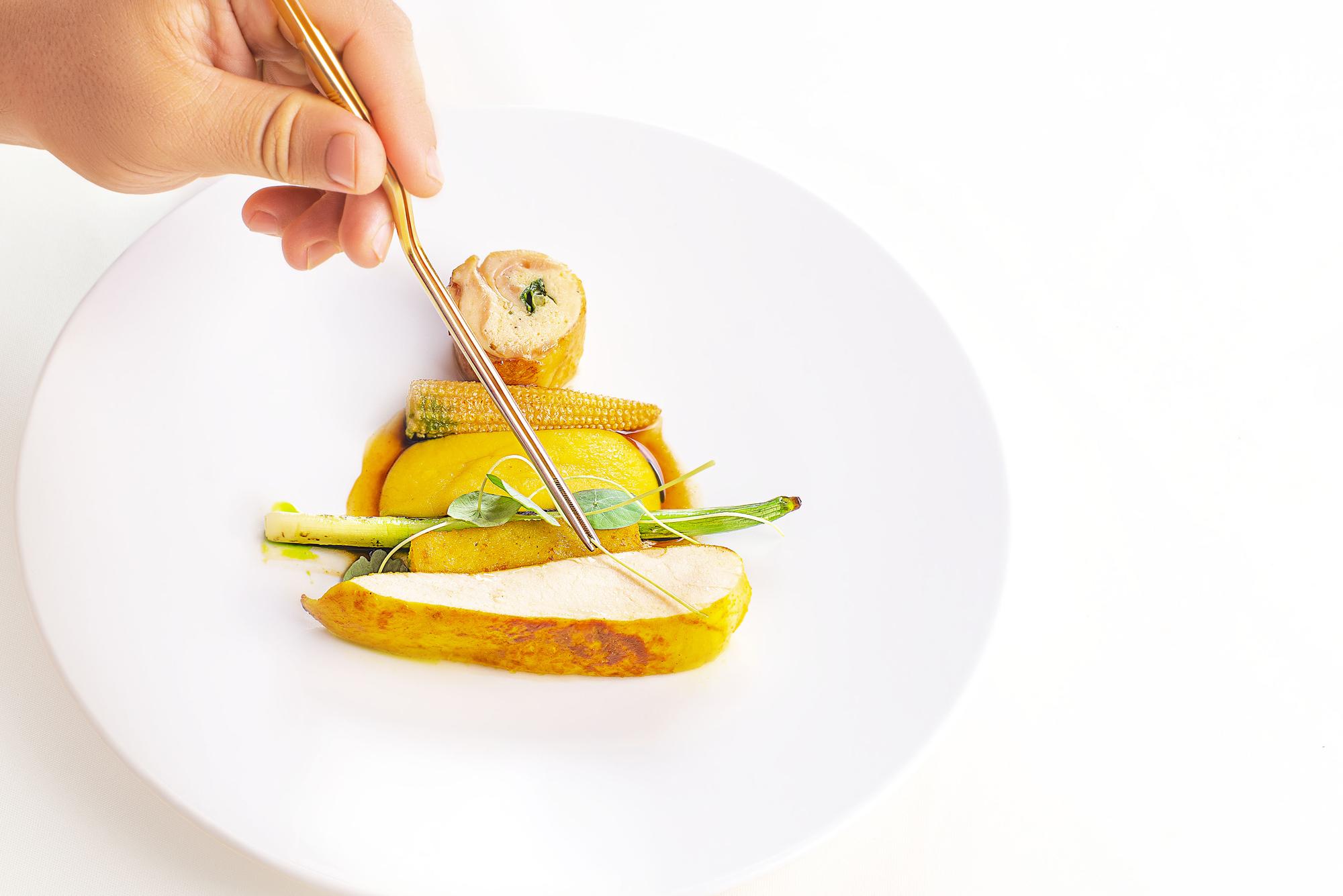 Dettaglio impiattamento con mano dello chef